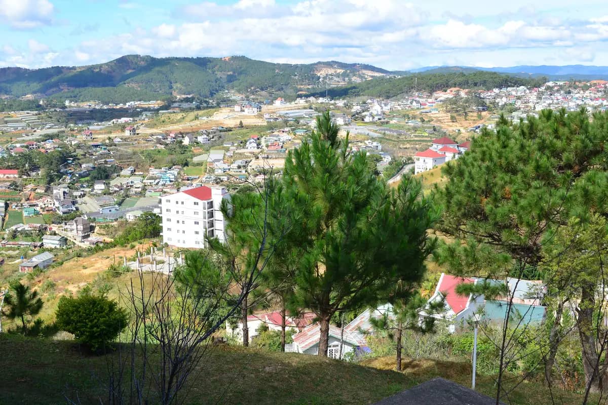 Da Lat's houses spread over green hills among pine trees, with mountains on the horizon
