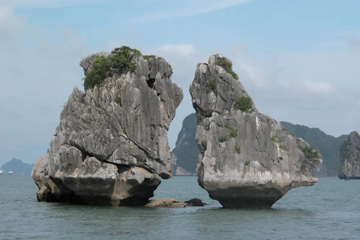 Trong Mai, the Rooster and Hen, two limestone rocks leaning toward each other out of the water in Ha Long Bay