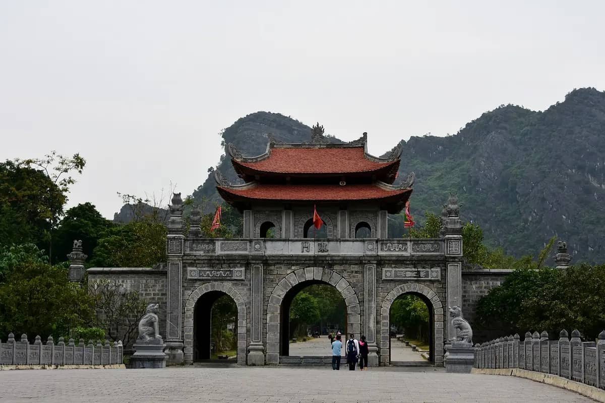 The stone gateway to the temple of Emperor Dinh Tien Hoang at Hoa Lu, with a steep limestone peak rising behind it