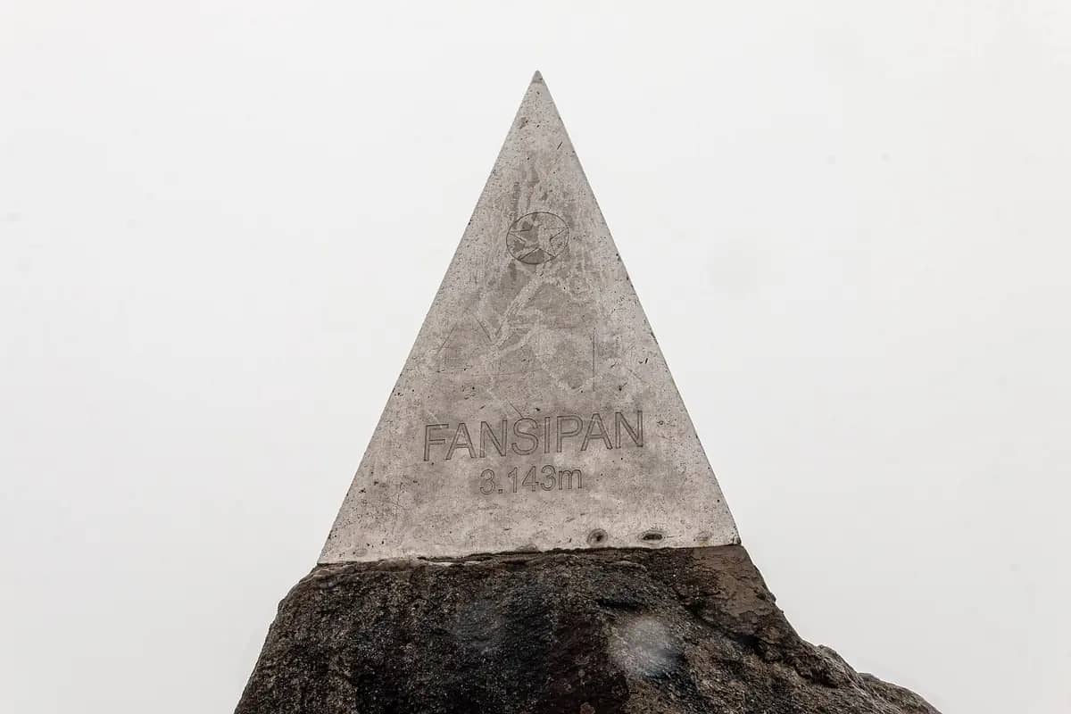 The pyramid summit marker on Fansipan, engraved Fansipan 3,143 m, on a rock against white cloud