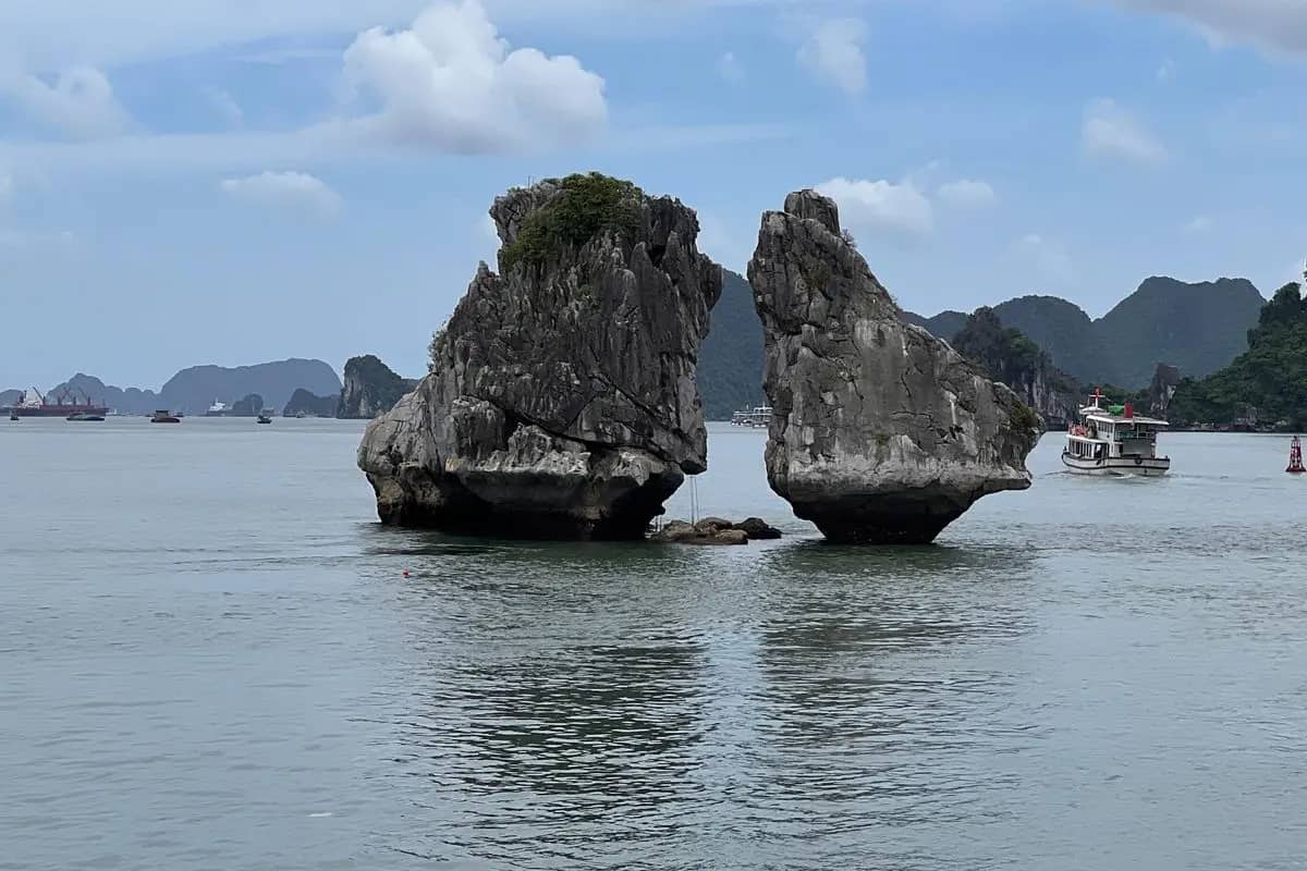 Trong Mai, the cock and hen islets, two rocks facing each other above the water, a tour boat passing