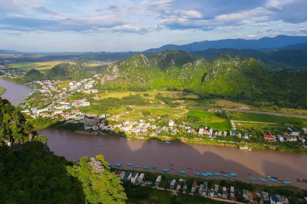 Phong Nha town strung along the Son River below green karst hills, seen from the air
