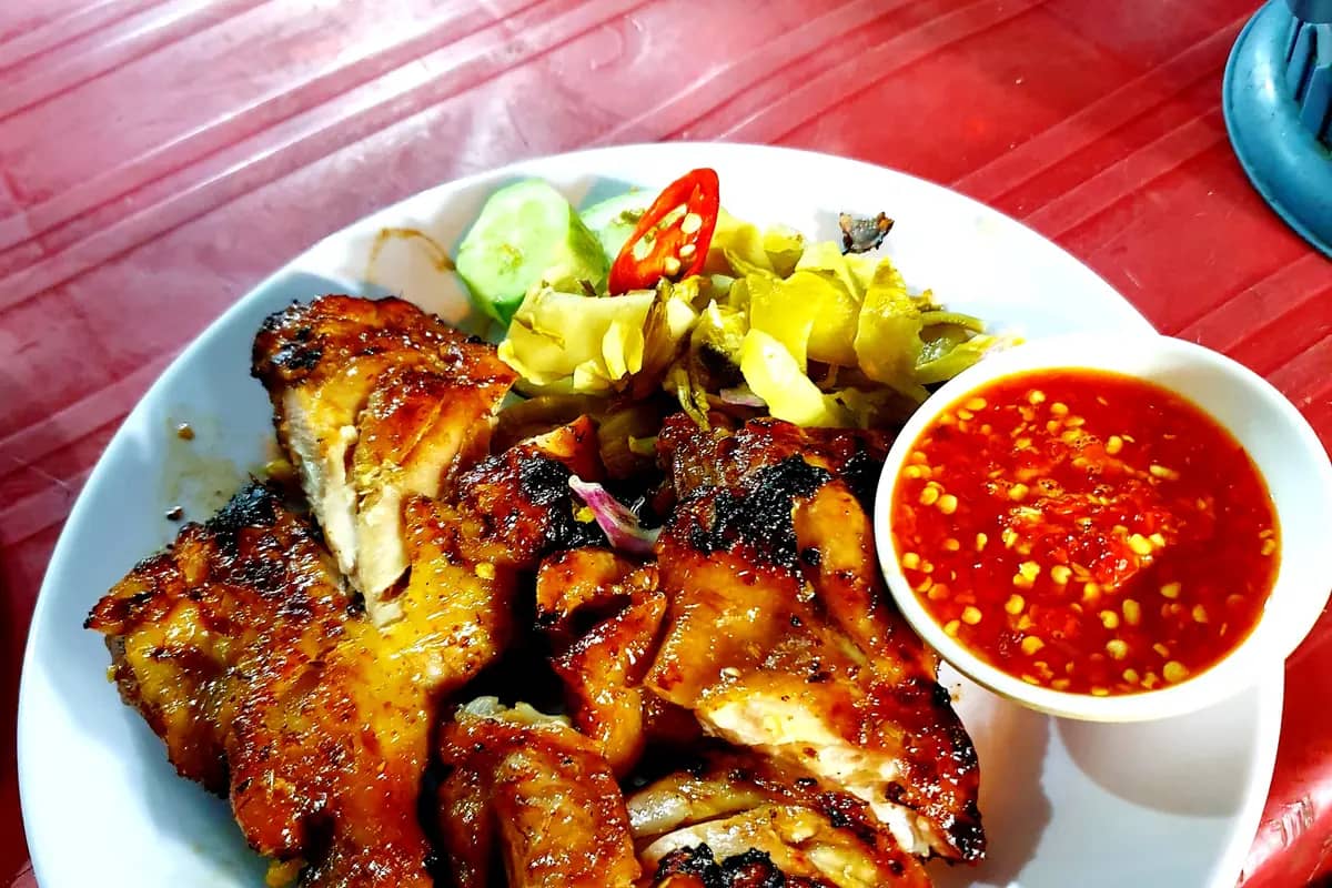 A plate of Vietnamese grilled chicken with pickled vegetables and a chilli dip