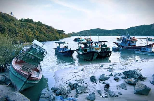 Fishing boats moored in a calm bay below green hills on Con Dao