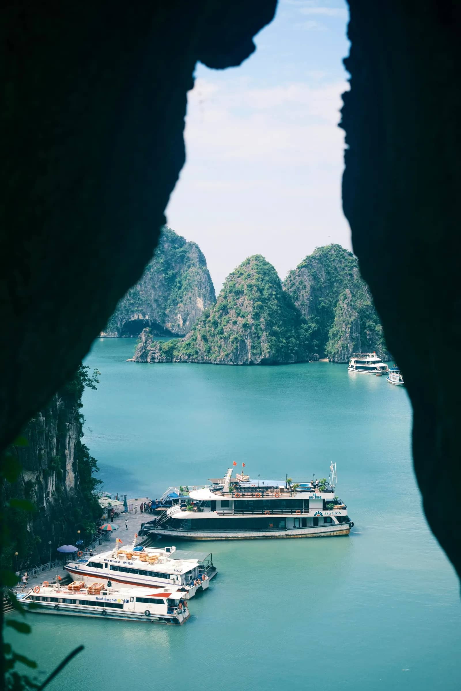 Tour boats at a pier, framed by the rock of a cave mouth