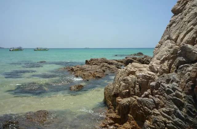 A rocky shore and clear turquoise water at Quy Nhon, boats in the distance