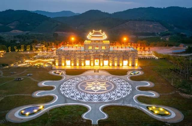The pagoda complex of Tay Yen Tu lit up at dusk below forested hills