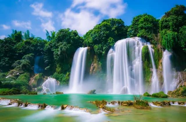 Ban Gioc Waterfall falling into a turquoise pool between green hills