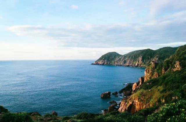 Green cliffs dropping into the blue sea on the Phu Yen coast