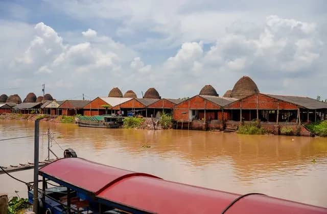 Rows of domed red brick kilns along the Mang Thit river in Vinh Long, a boat roof in front