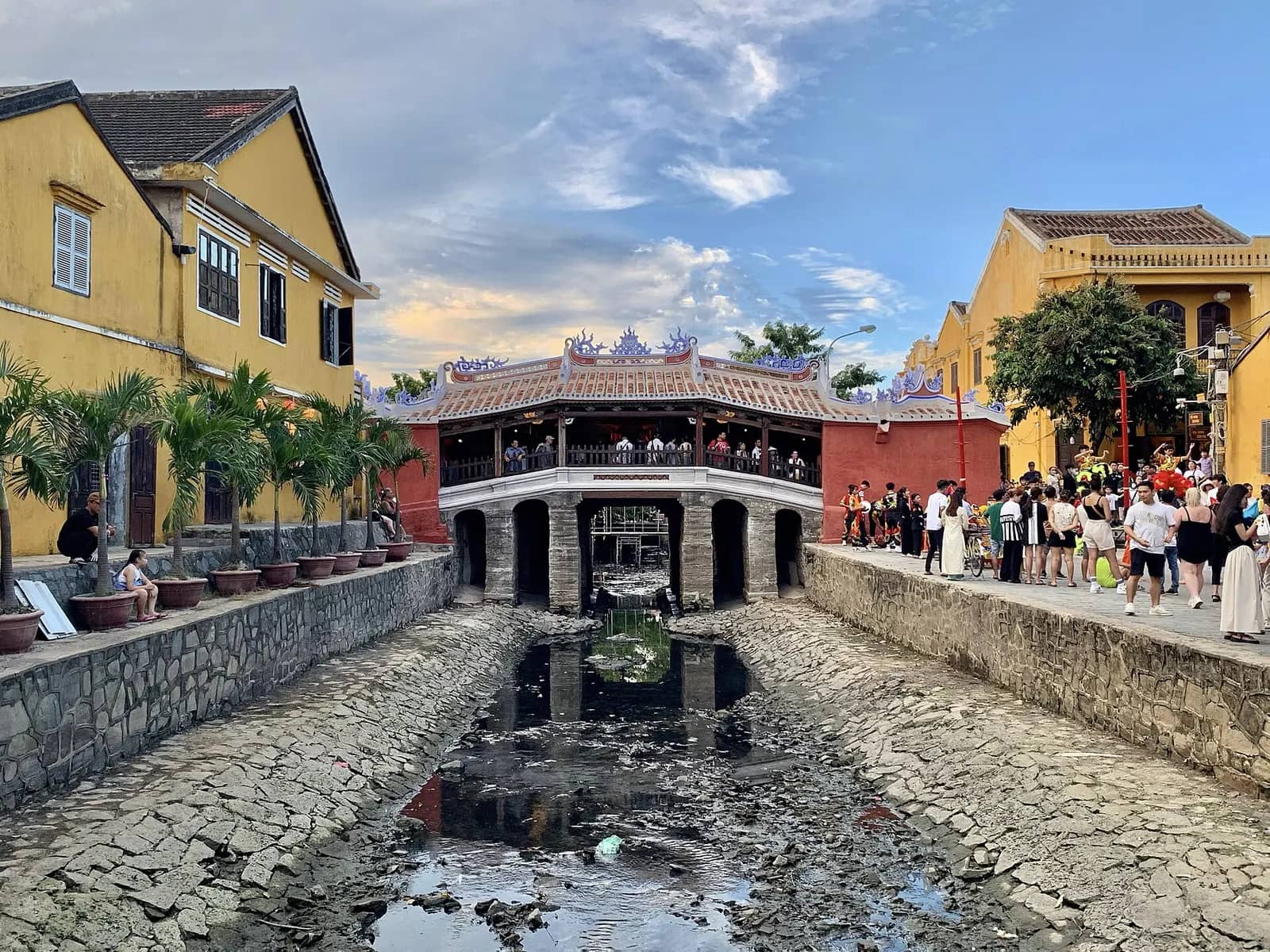 The Japanese Covered Bridge after its 2024 renovation, its tiled roof over a stone canal lined with yellow houses and visitors