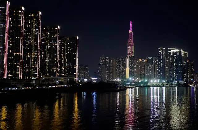 Landmark 81 lit pink above the Ho Chi Minh City skyline, reflected in the Saigon River at night
