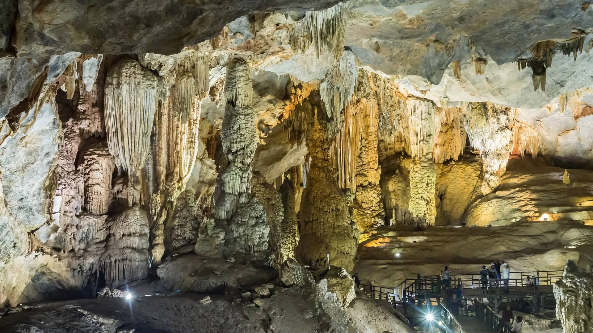 Stalactite formations and a wooden walkway inside a Phong Nha cave chamber