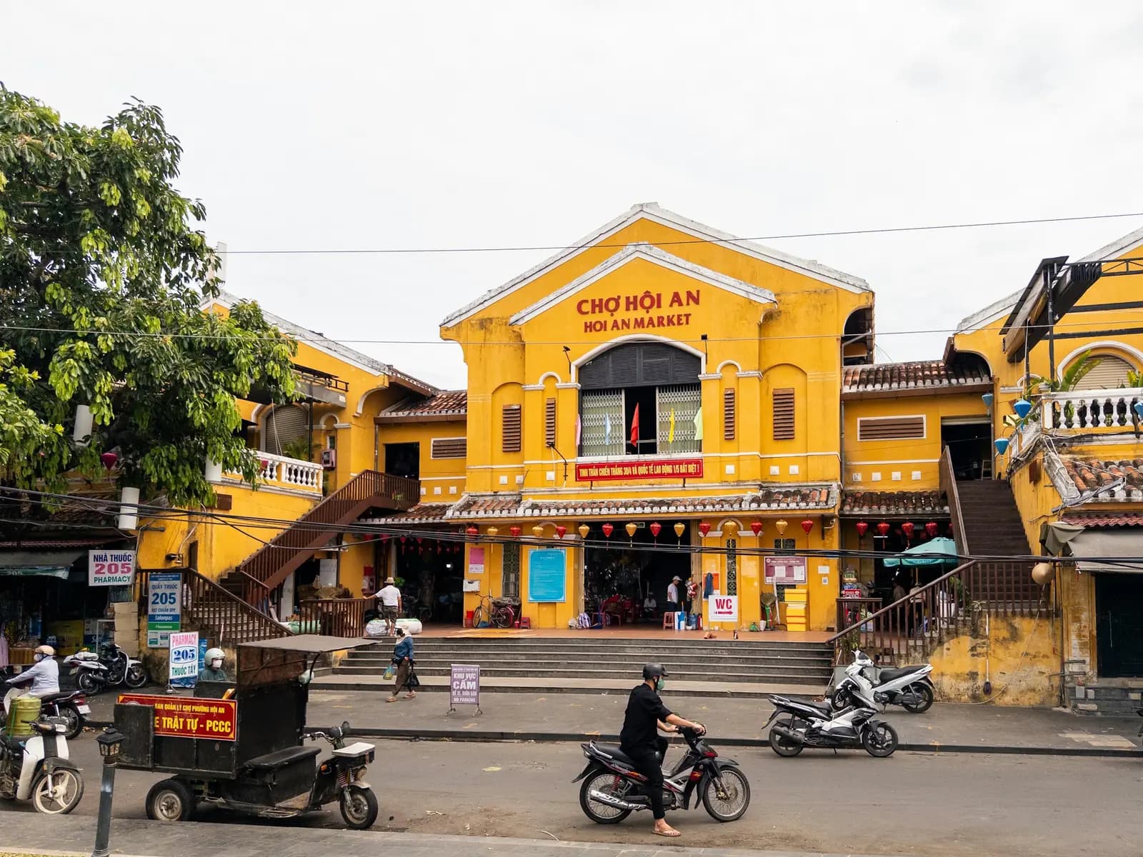 Hoi An's yellow market building, with people and scooters out front