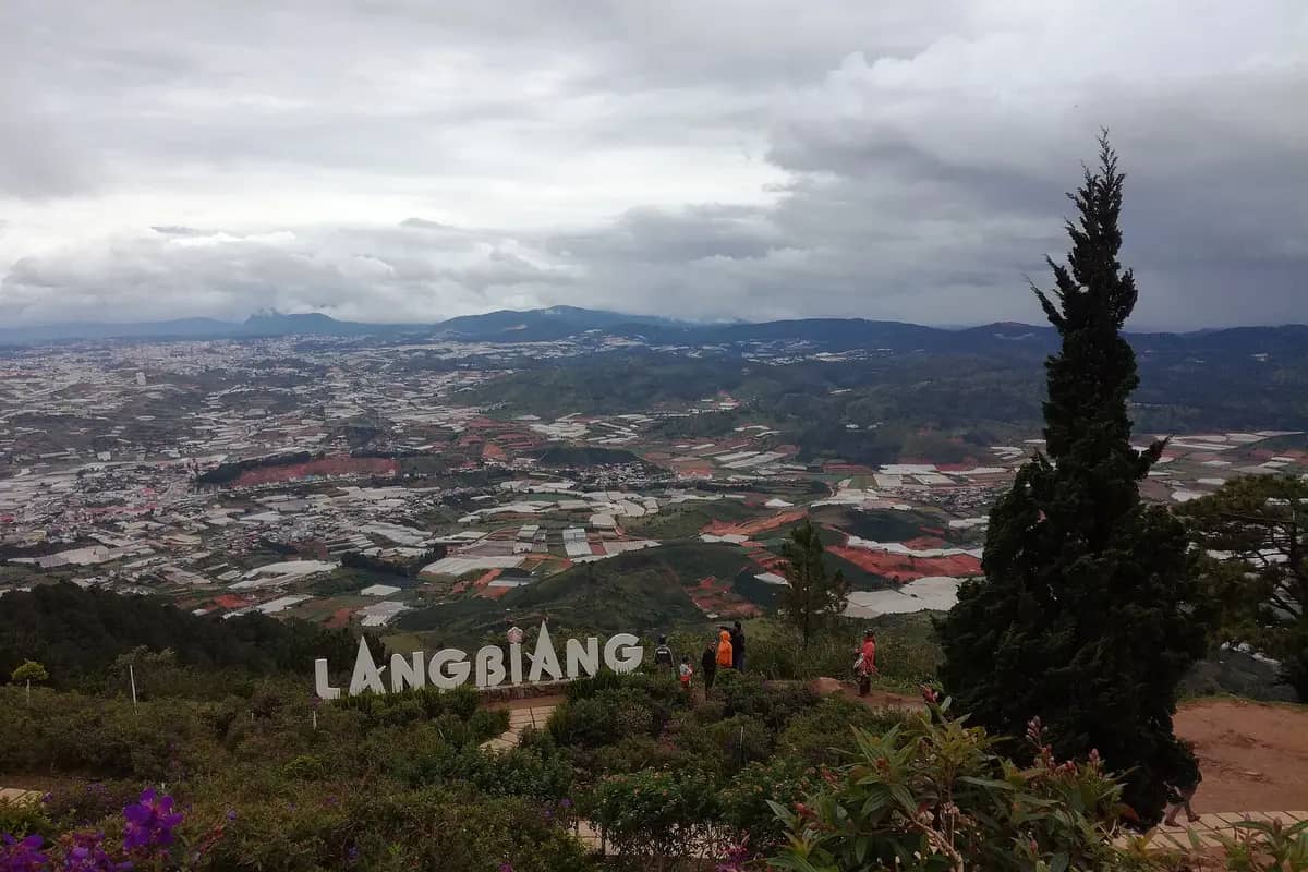 The Langbiang sign on the summit, with farmland and greenhouses spread across the valley below