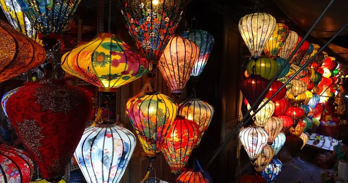 Dozens of glowing silk lanterns in red, yellow, white and blue hanging at a lantern shop in Hoi An on a full moon night