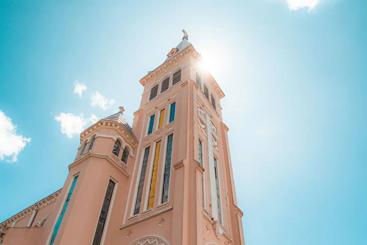 The pink bell tower of Da Lat Cathedral against a blue sky