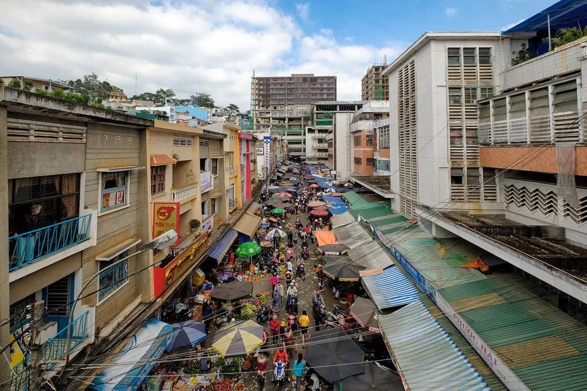 Stalls under awnings and umbrellas in the street beside Da Lat market, seen from above