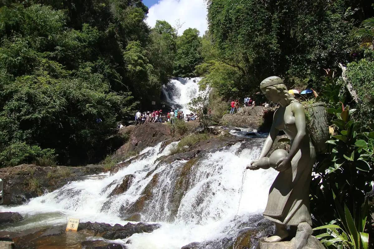 Datanla falls tumbling over the rocks, a statue of a woman with a water jar in front