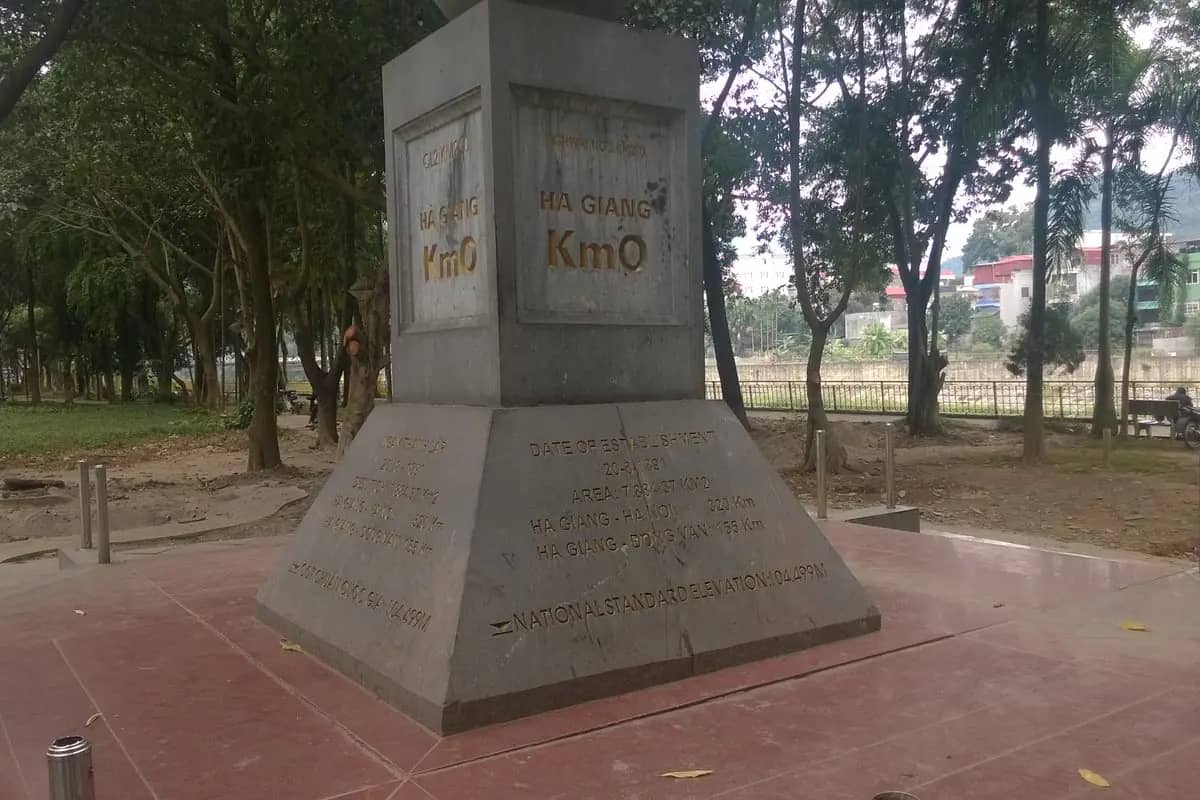 The grey stone Km0 marker in Ha Giang city, with the distances to Hanoi and Dong Van carved on its base