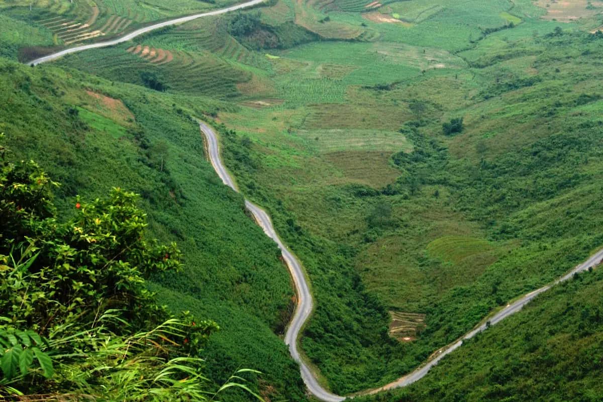 QL4C winding up through green fields and slopes, seen from the top of the Bac Sum pass