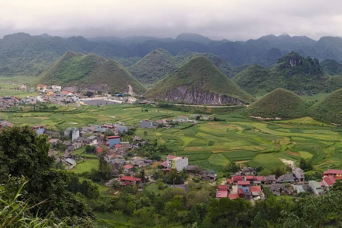 The two rounded Twin Mountains rising from the rice fields and houses of the Quan Ba valley
