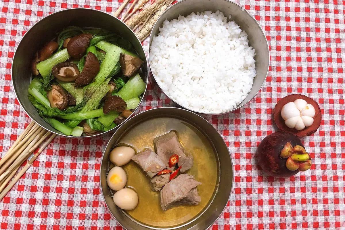 A shared home-style meal of rice, stir-fried greens with mushrooms and pork with eggs in broth