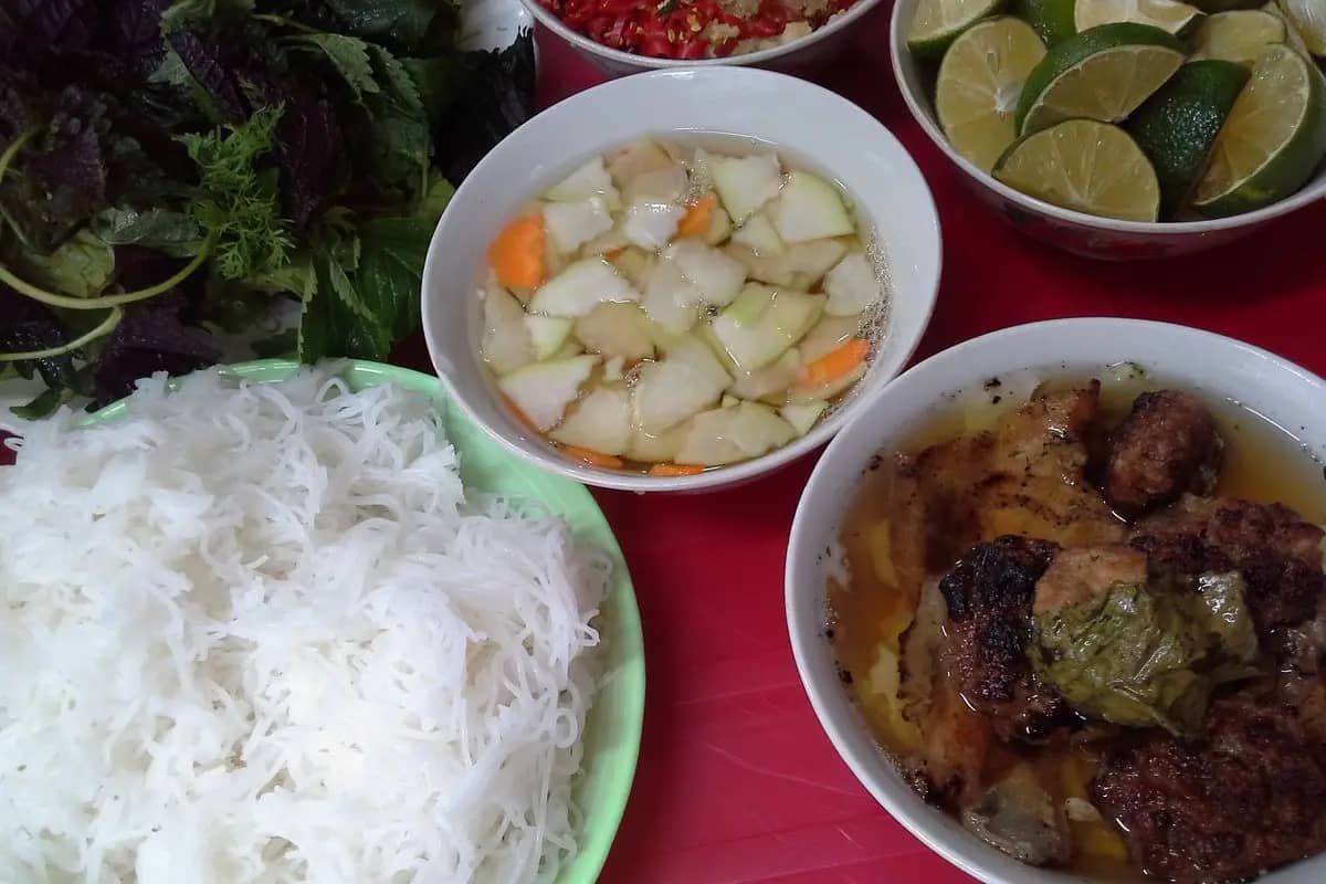 A bun cha meal on Hang Manh street: grilled pork in a fish-sauce broth with pickled green papaya, rice noodles, herbs and lime
