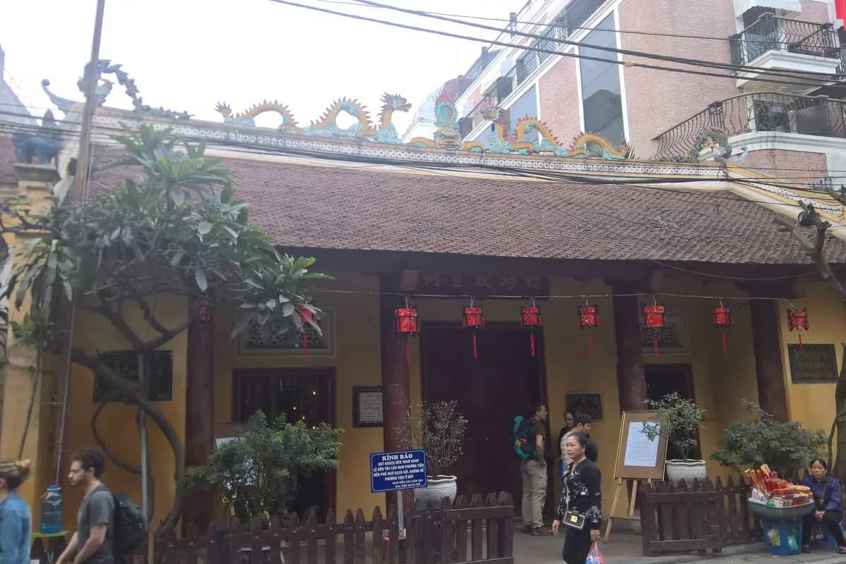 The yellow front of Bach Ma Temple on Hang Buom, dragons on the roof and red lanterns over the door