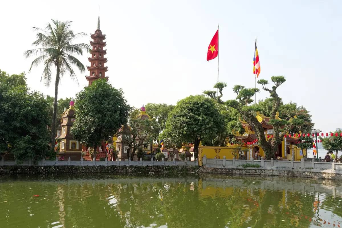 The red tower of Tran Quoc Pagoda and its yellow walls on the island, reflected in the water