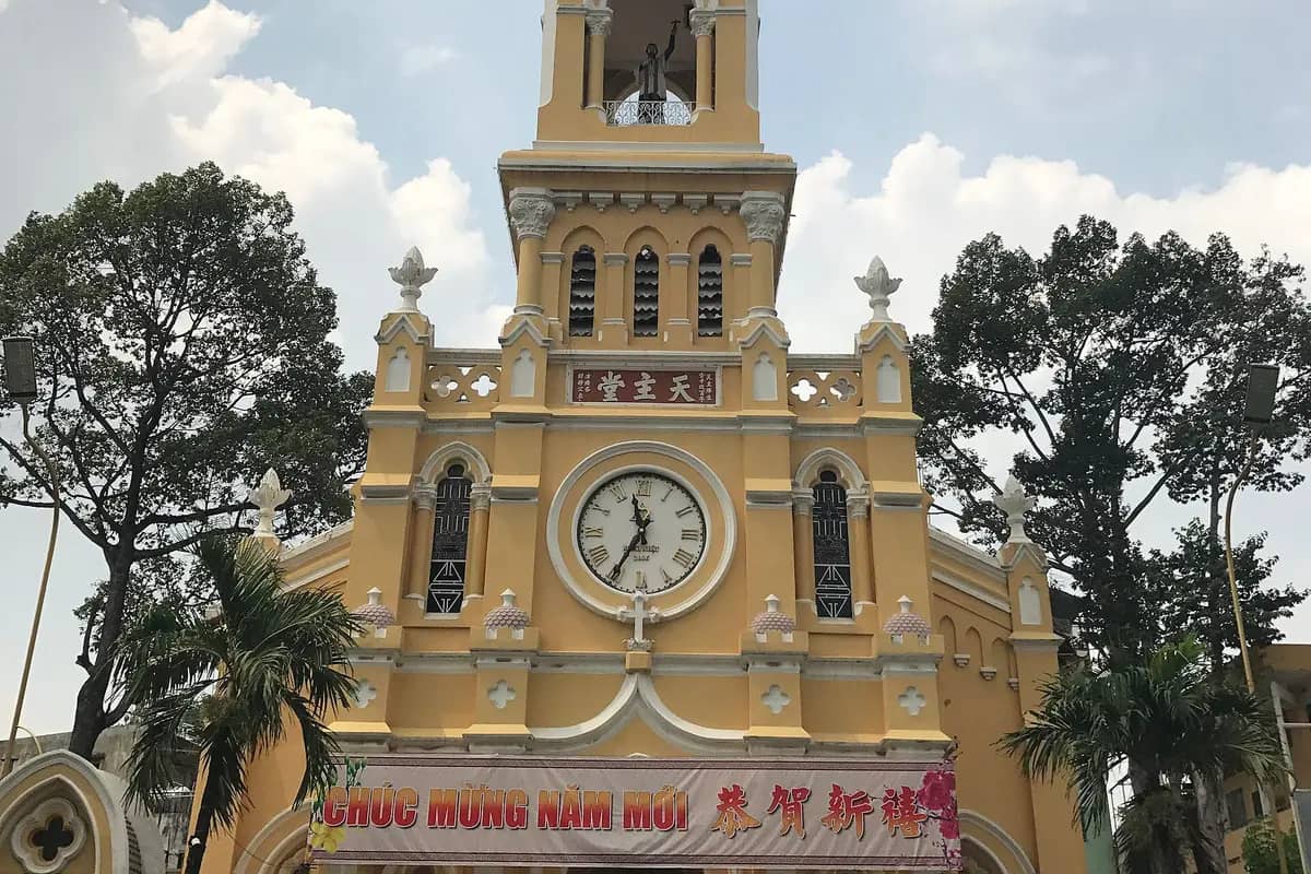 The yellow front and clock of Cha Tam Church, Chinese characters above the door