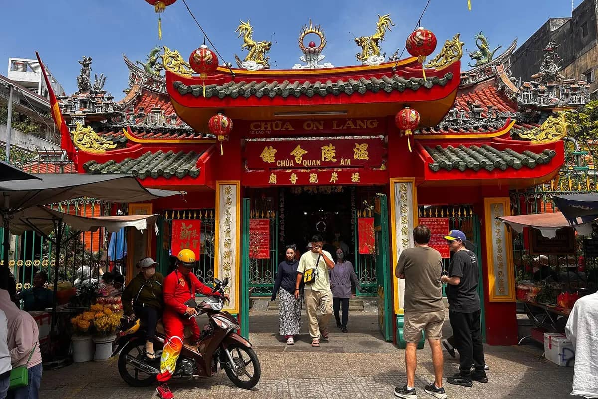 The red gate of Quan Am Pagoda on Lao Tu Street, people coming and going