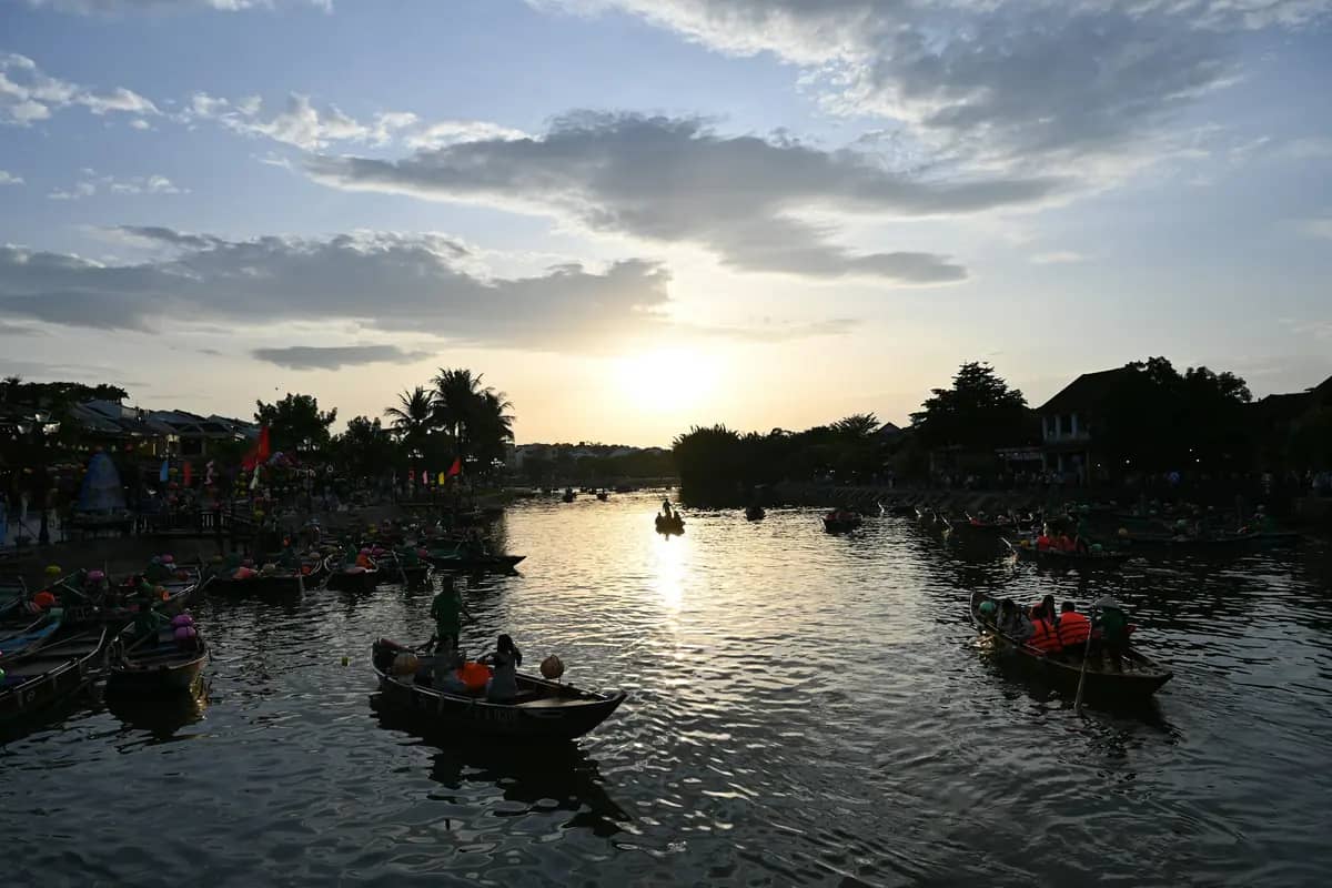 Small boats on the Thu Bon River at Hoi An as the sun sets behind the old town