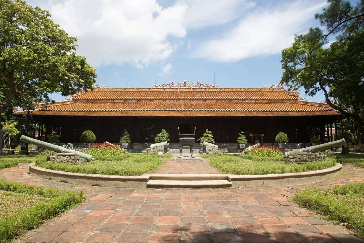 Long An Palace, home of the Hue Royal Antiquities Museum, behind a paved courtyard with old cannons