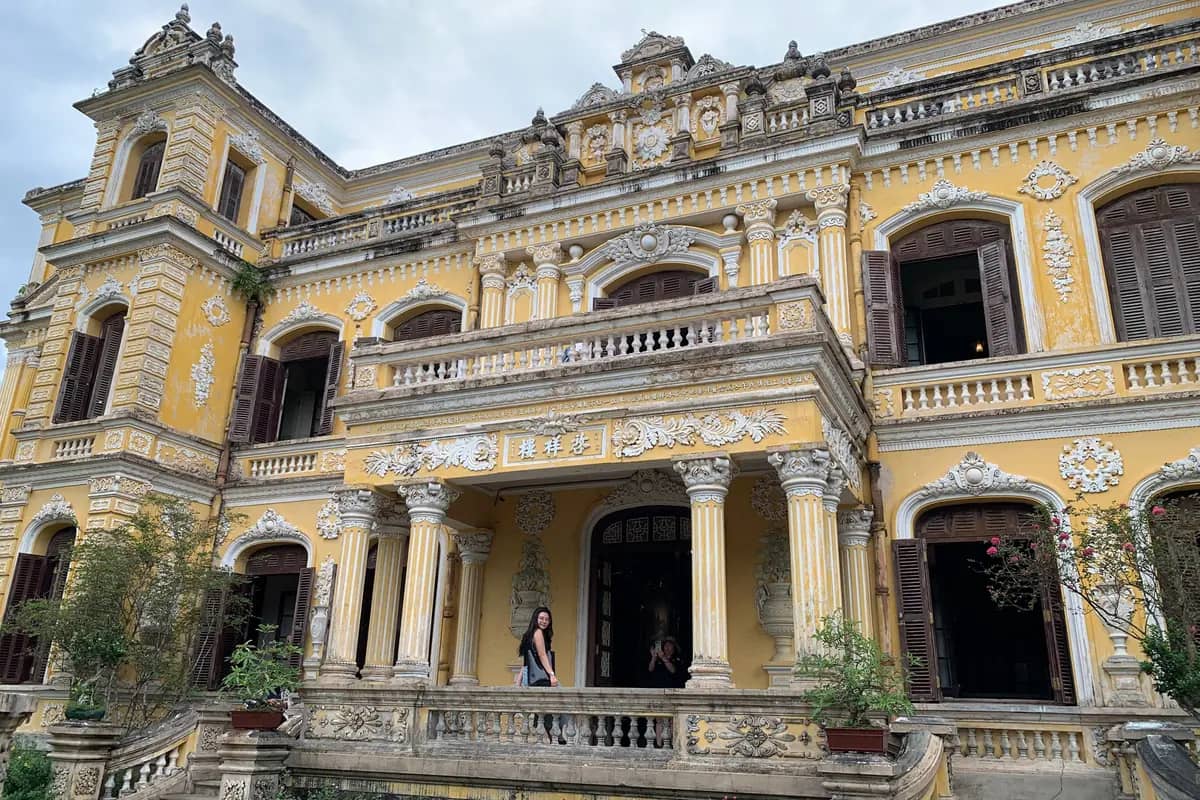 The ornate cream and yellow facade of An Dinh Palace with its columned porch