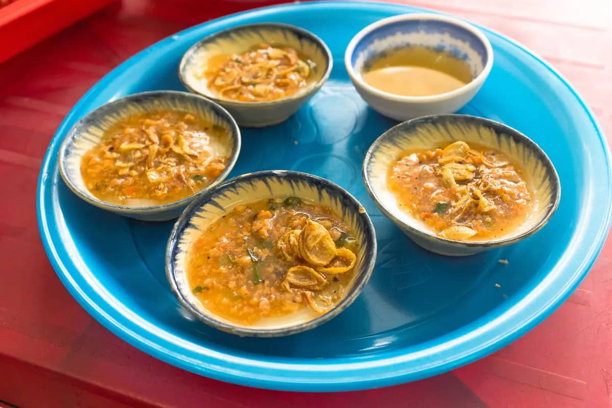 Banh beo in small saucers topped with shrimp and fried shallots, with a dish of fish sauce