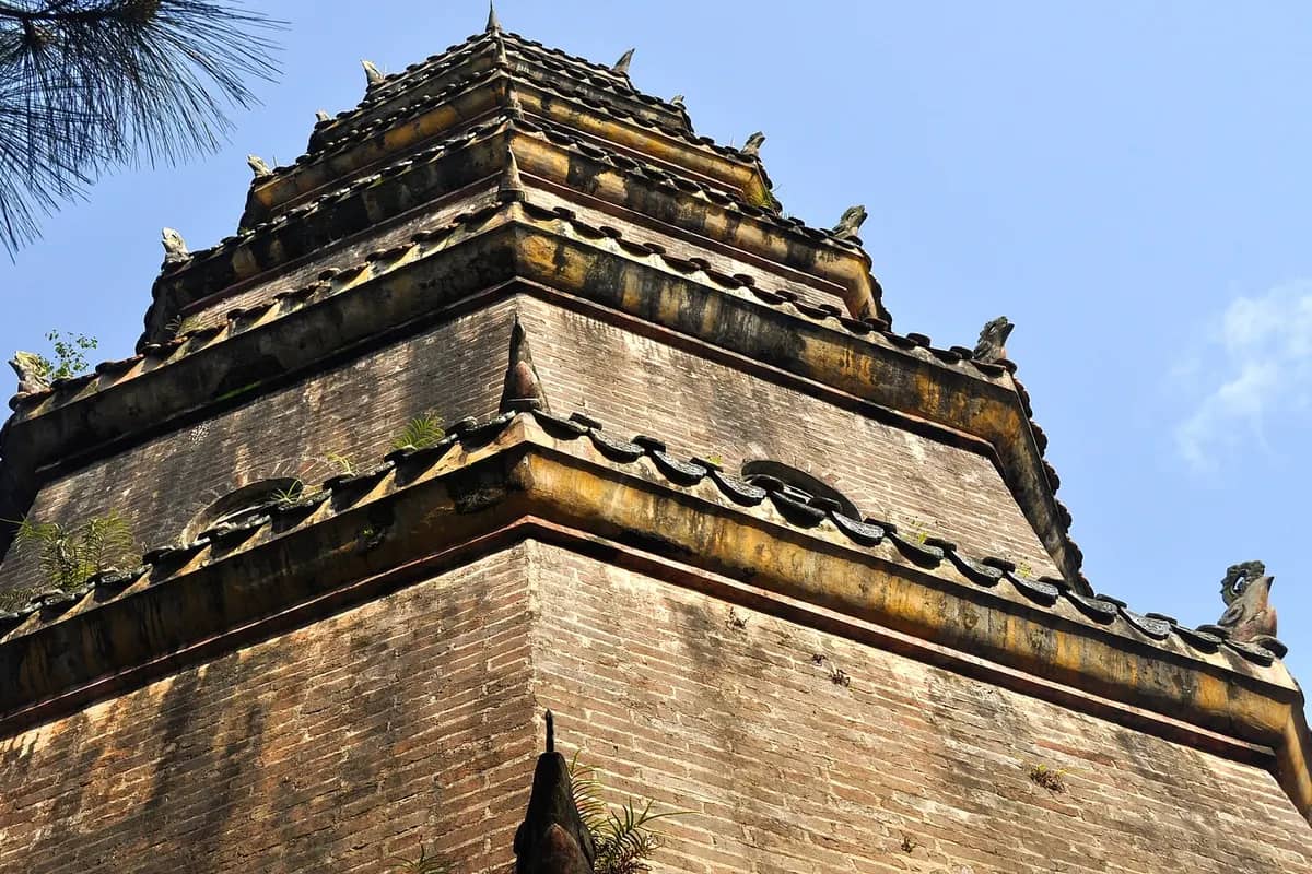 The upper tiers of the Phuoc Duyen tower at Thien Mu Pagoda against a blue sky