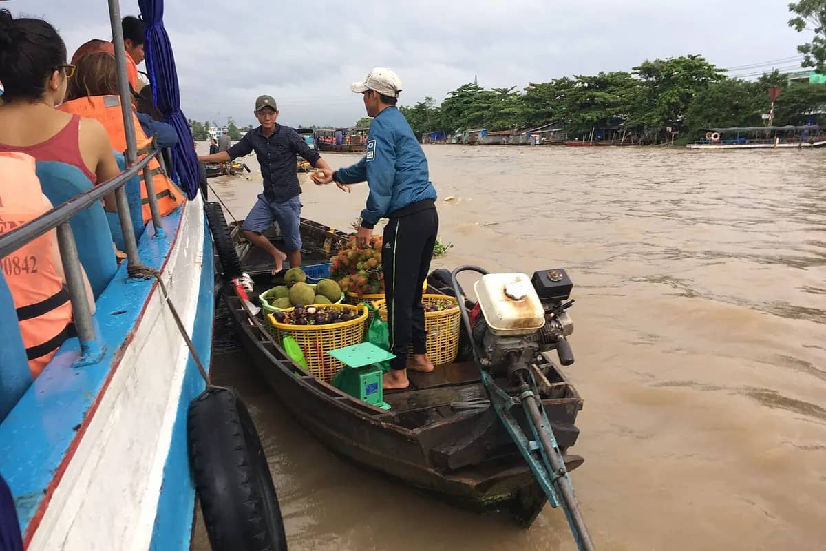 Tourists in a market boat buying fruit from a sampan at Cai Rang