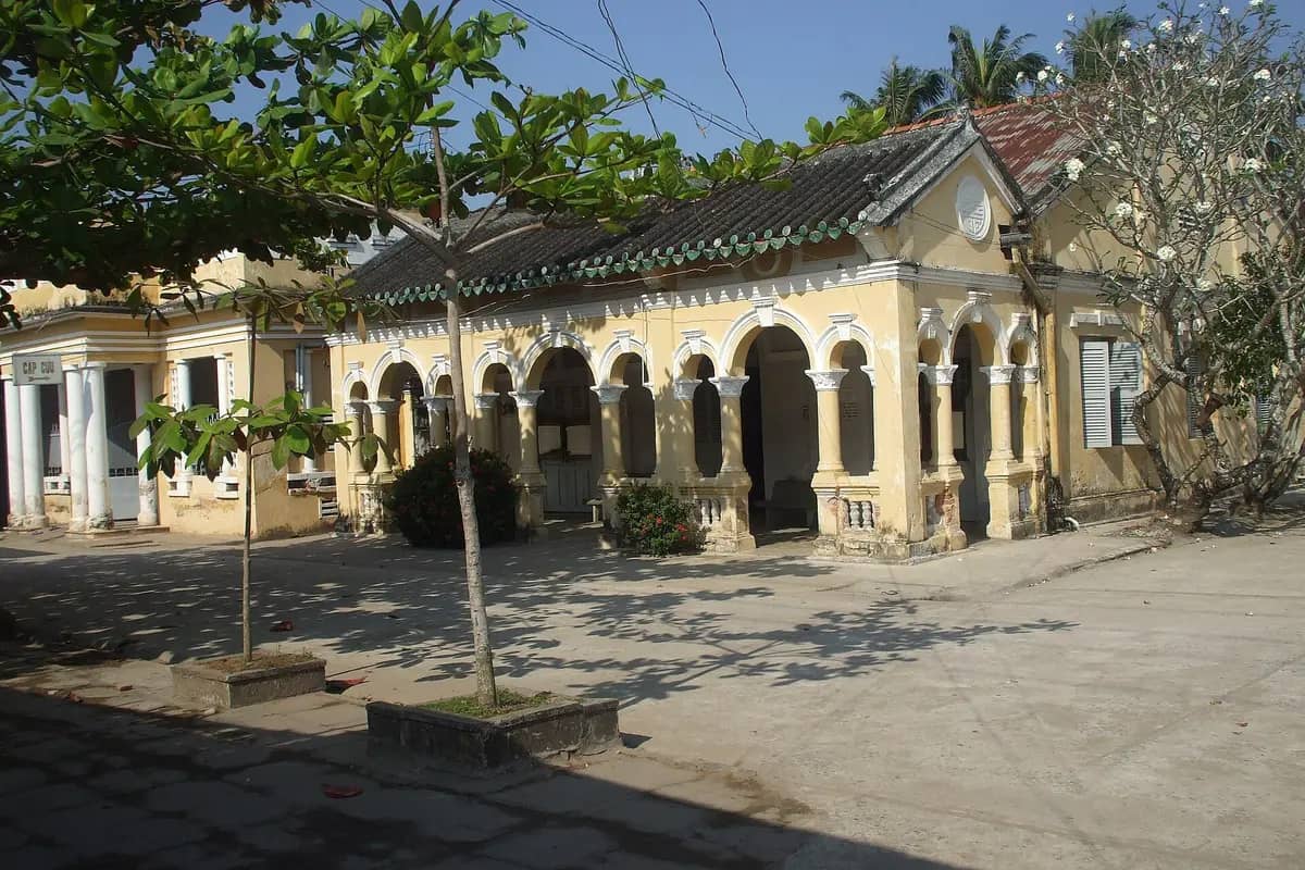 The yellow arched front of the Binh Thuy ancient house under the trees