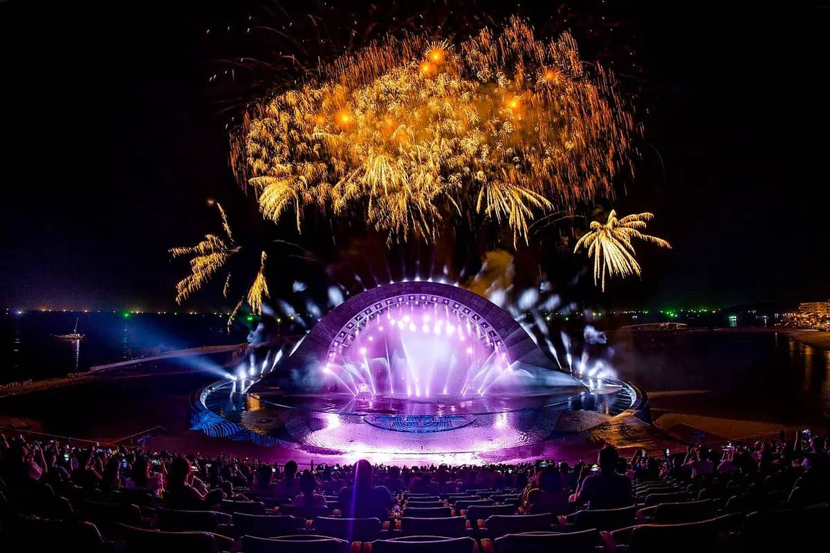 Fireworks above the lit stage of the Kiss of the Sea show, the audience in front