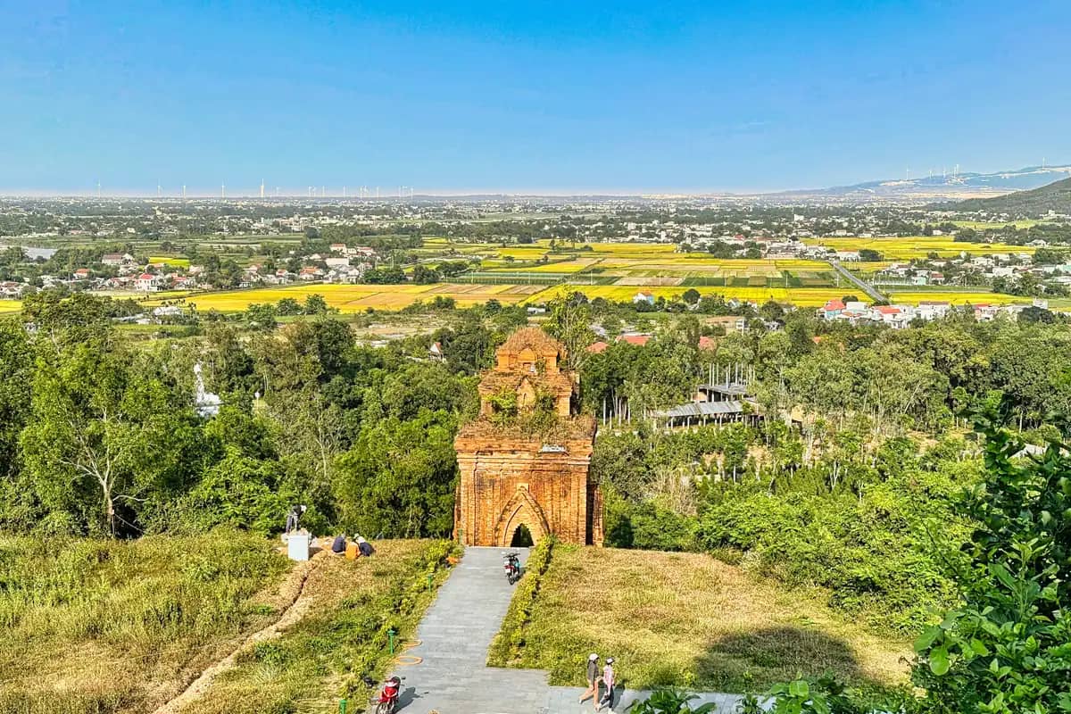A brick Cham gate tower below the Banh It hilltop, rice fields and villages spreading to the horizon