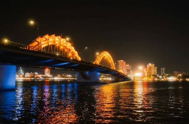 Dragon Bridge lit orange over the Han River in Da Nang at night