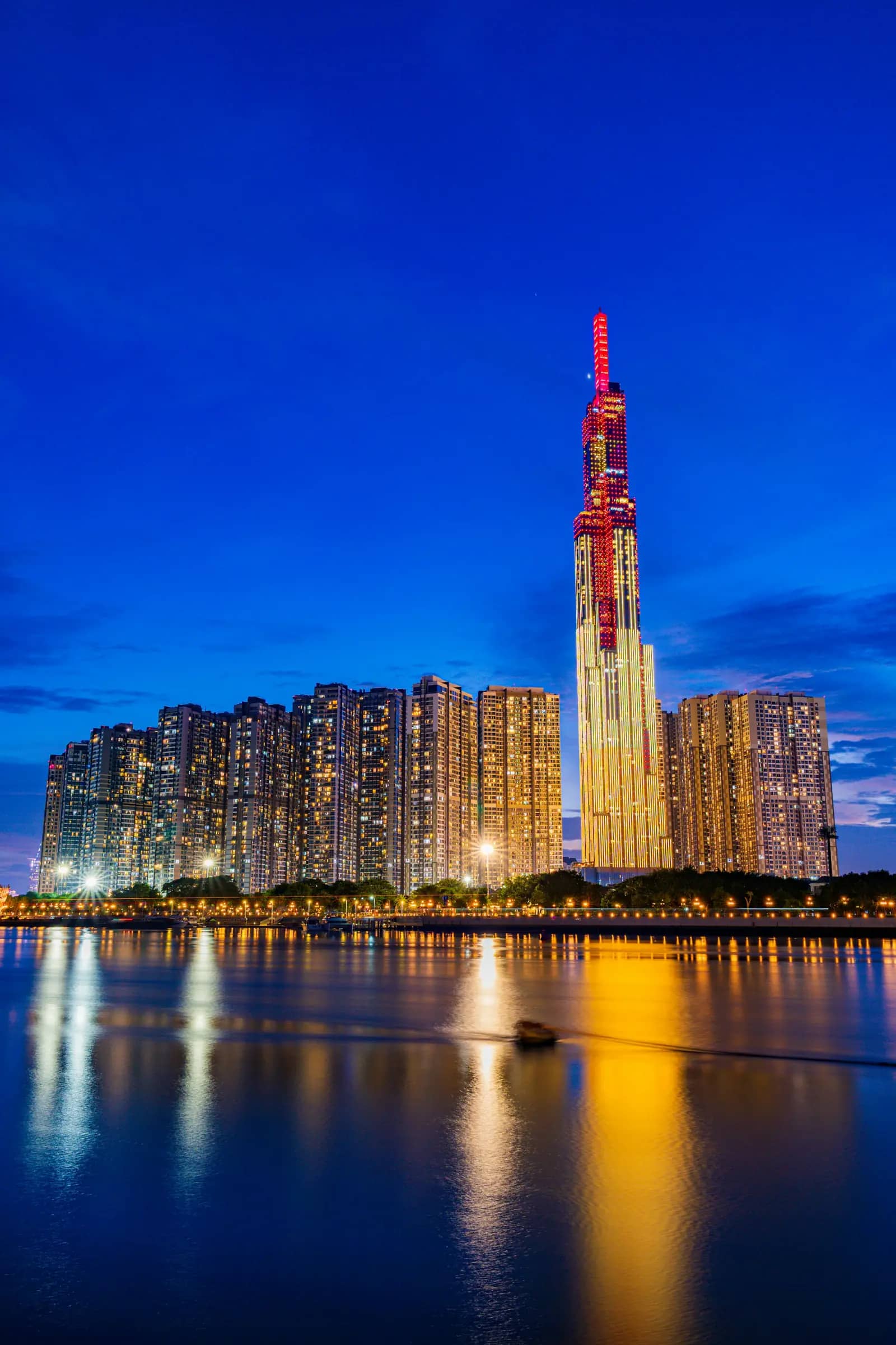 Landmark 81 and the apartment towers beside it reflected in the river at dusk