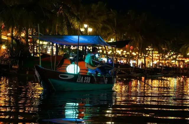 A boat hung with glowing lanterns on the river in Hoi An at night