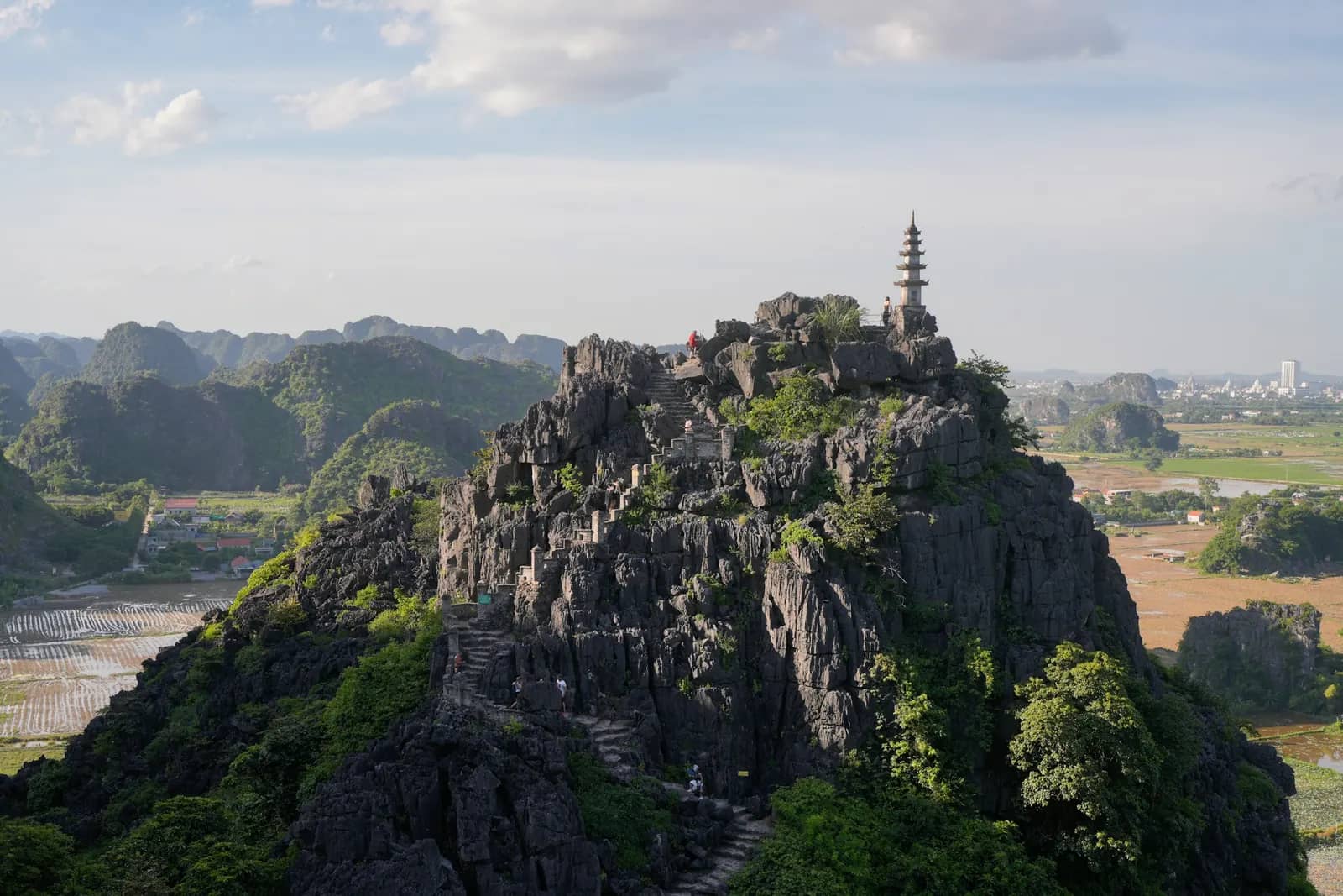 A pagoda on top of a rocky karst above the green plain at Hang Mua