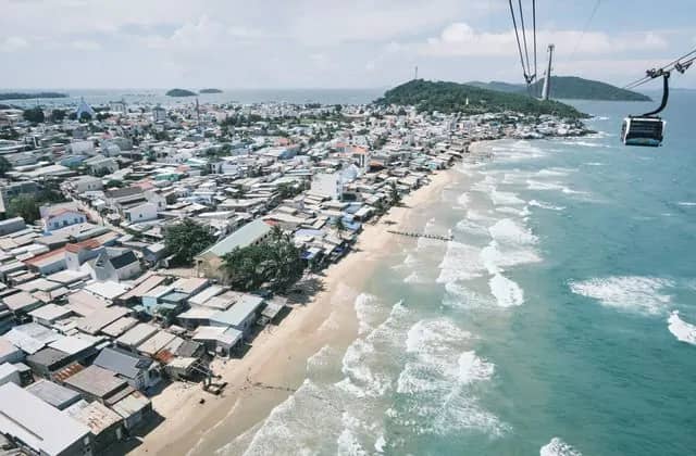 A coastal town along a sandy beach and turquoise sea on Phu Quoc, seen from above
