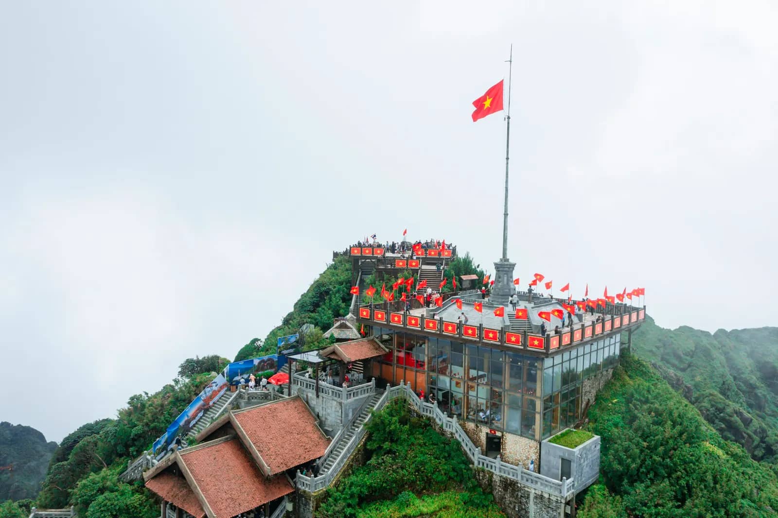 A temple complex on a misty peak, the Vietnamese flag above it