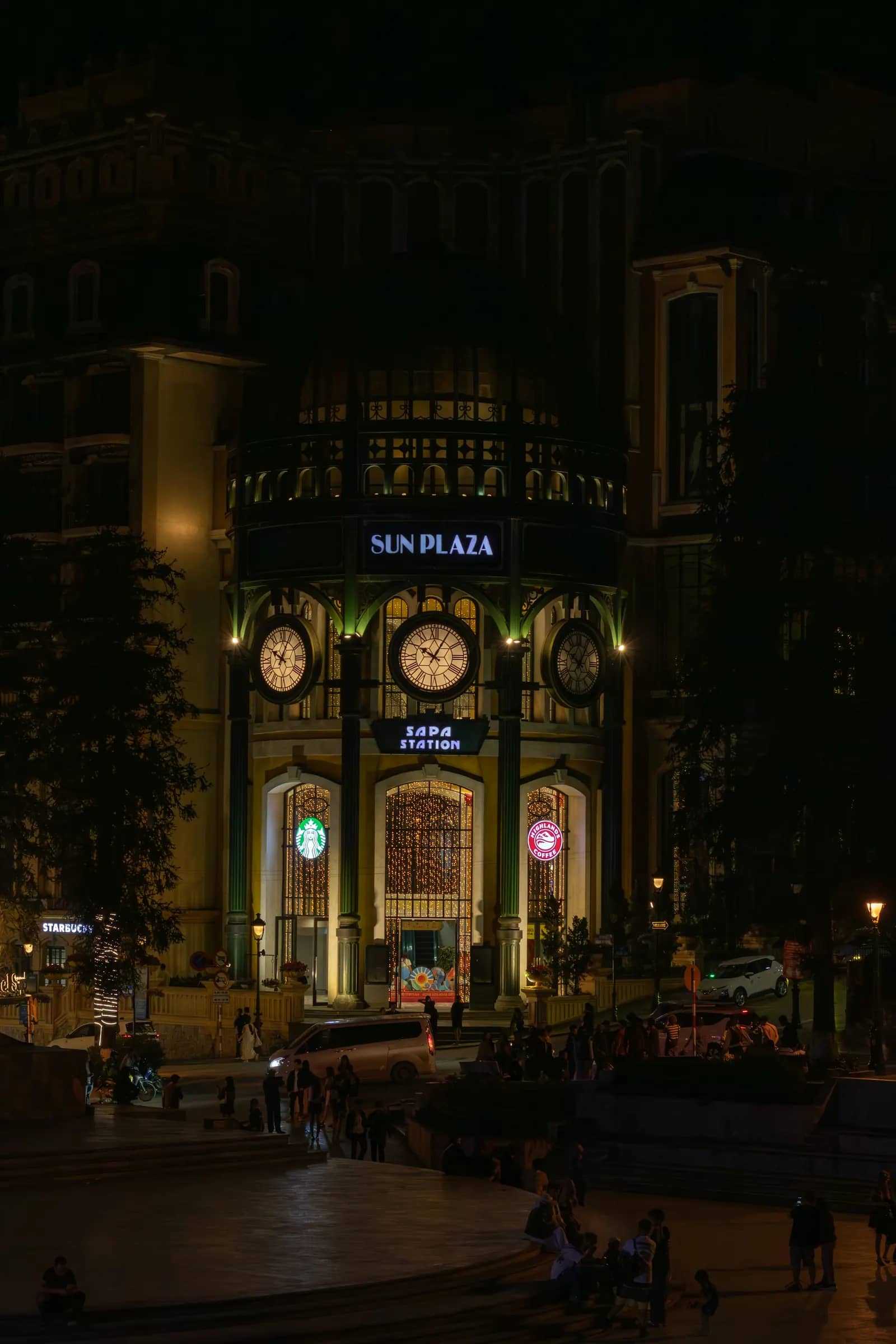 The Sun Plaza building with its clocks lit up at night