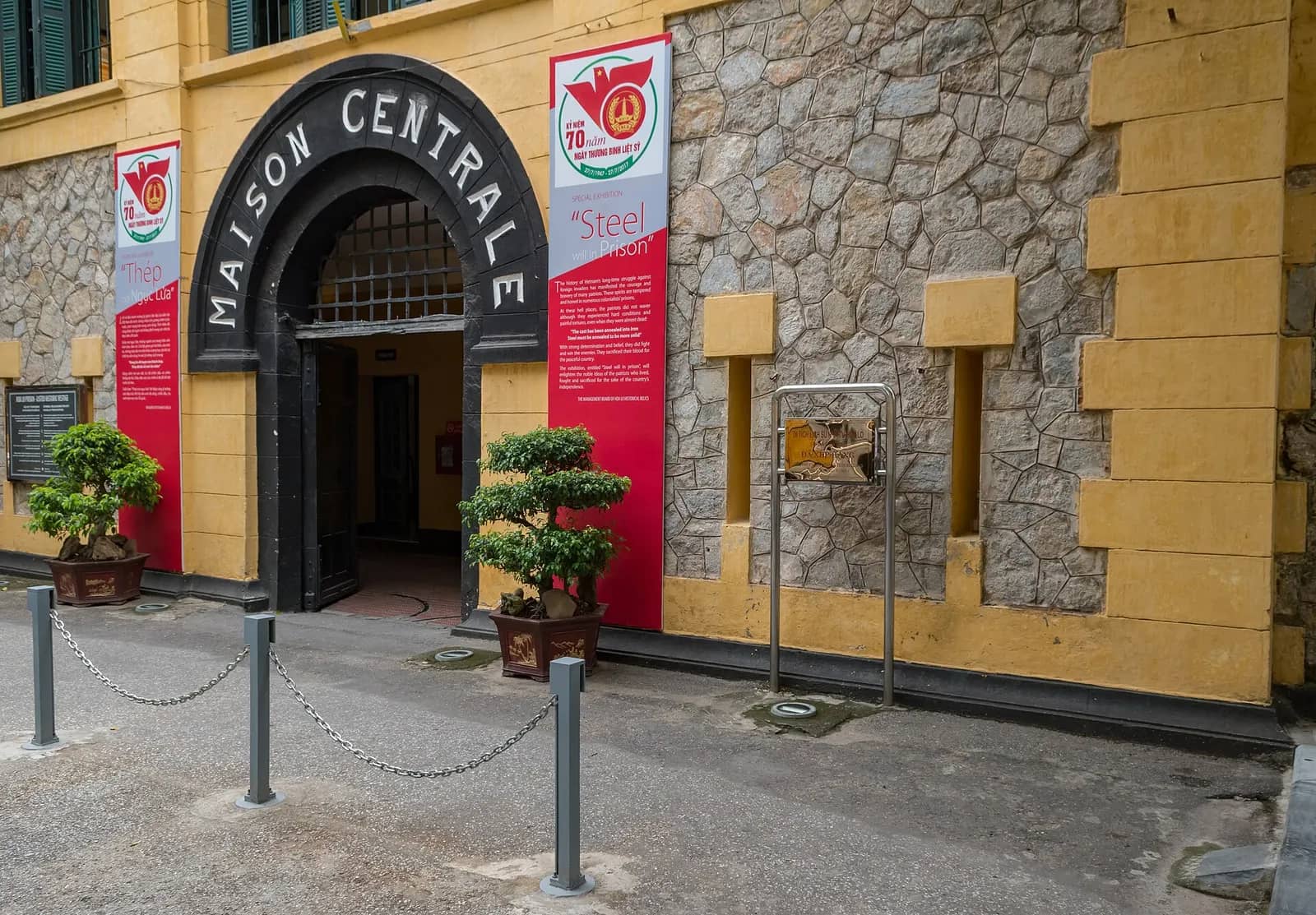 Yellow stone gatehouse of Hoa Lo Prison with the words Maison Centrale arched over the entrance