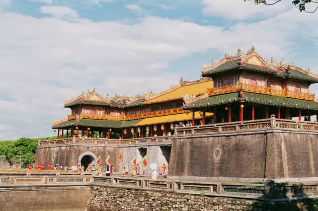 Ngo Mon, the main gate of Hue's Imperial City, on a sunny day, with guards in costume carrying flags below it
